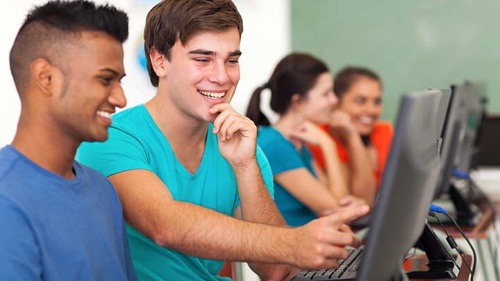 Two high school students study by discussing a recorded video presentation in computer lab