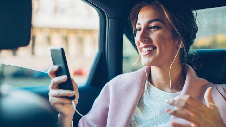 Woman in a car smiling using her phone